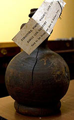 Cracked wooden sphere with paper label resting on screw top.